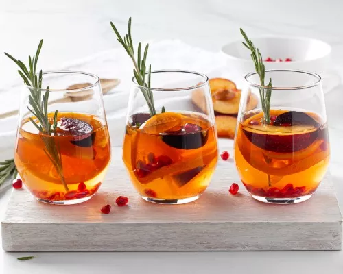 rois verres de sangria blanche avec glaçons, brins de romarin et fruits tranchés