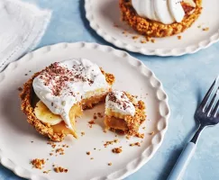 Deux tartes banoffee en portions individuelles sur des assiettes blanches, l'une avec un morceau enlevé.