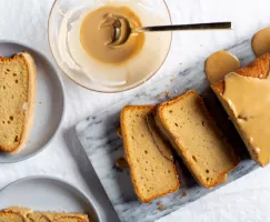 Tranches de gâteau à la bière couvert de glaçage sur une plaque de marbre, avec un bol de glaçage et deux assiettes garnies de t