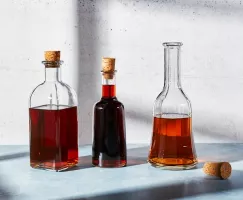 Trois bouteilles en verre de sirop simple de sucre brun sur un comptoir, deux bouchées et une non bouchée.