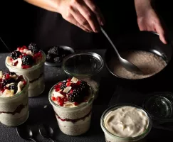 Pouding chia vanille et cardamome dans une tasse, garniture de mûres, de noix de coco et d’arilles de grenade