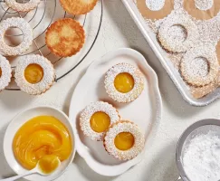 Biscuits au curd d'agrumes sur un plateau avec des biscuits non finis sur une grille de refroidissement