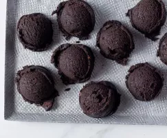 Dix boules de pâte à biscuits au chocolat noir sur un plateau blanc