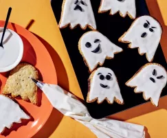 Tartelettes en forme de fantômes, certaines décorées avec des visages en glaçage noir sur du glaçage blanc