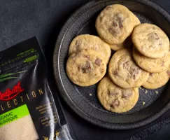 Biscuits au sucre avec morceaux de chocolat au lait présentés sur une assiette noire avec une serviette noire, sur comptoir en a