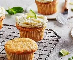 Cupcakes style mojito sur une grille de refroidissement, certains garnis d'un glaçage à l'hermine et garnis de citron vert.