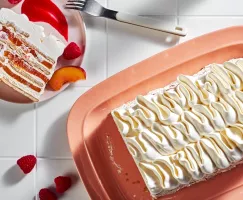 Gâteau glacé Peach melba vu de l'extrémité tranchée, révélant des couches de biscuits, de crème, de pêches et de framboises.