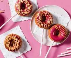 Donuts glacés sur bâtonnets avec un filet de beurre d'arachide et des arachides concassées