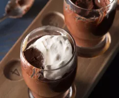 Deux pots de crème au chocolat partiellement mangés dans des verres de bière sur un plateau de dégustation