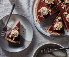 Tarte au chocolat chai végétalien sans cuisson sur un plateau avec deux tranches coupées, une servie sur une assiette