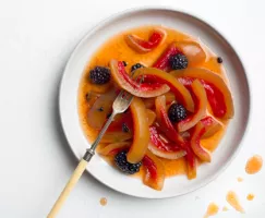 Une assiette de blanc de melon d’eau mariné et de mûres avec une fourchette
